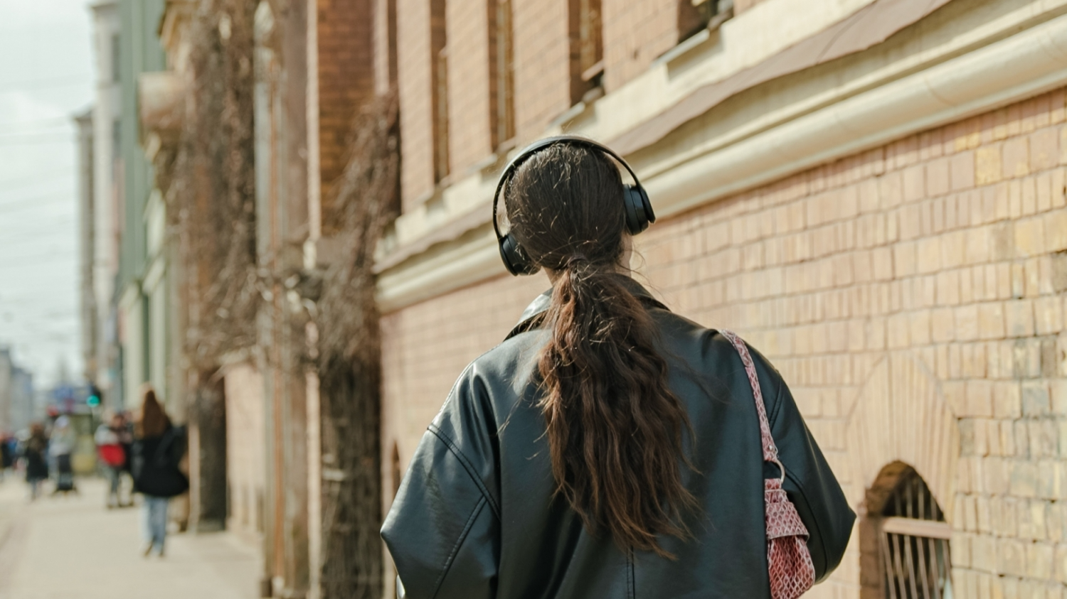 Meitene iet pa ielu un austiņās klausās mūziku